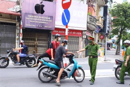 Công an phường Bạch Mai (quận Hai Bà Trưng) kiểm tra những người ra đường, sáng 26/7. (Ảnh: Hoàng Hiếu/TTXVN)