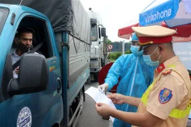 Lực lượng chức năng tỉnh Phú Thọ kiểm tra giấy xét nghiệm âm tính với COVID-19 của lái xe tải ở địa phương khác vào tỉnh Phú Thọ. (Ảnh: Trung Kiên/TTXVN)