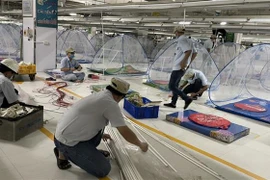 Công ty TNHH điện tử Foster (Việt Nam) sắp xếp màn, nệm ngủ để đón hơn 800 công nhân vào nhà máy lưu trú. (Ảnh: Chí Tưởng/TTXVN)