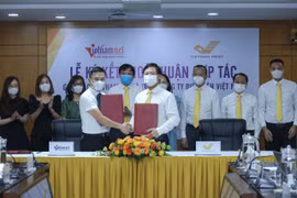 Tổng Biên tập Báo VietNamNet Phạm Anh Tuấn và Tổng Giám đốc Vietnam Post Chu Quang Hào ký thỏa thuận hợp tác. (CTV/Vietnam+)