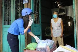 Đội hình Shipper áo xanh phường 11, thành phố Cao Lãnh, tỉnh Đồng Tháp mang nhu yếu phẩm cho hộ nghèo Đặng Thị Bé Tư. (Ảnh: Chương Đài/TTXVN)