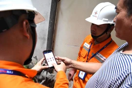 Nhân viên EVN hướng dẫn khách hàng kiểm tra hóa đơn điện. (Ảnh: evnhanoi)