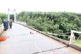 Hiện trường vụ xe va vào lan can cầu treo Bình Thành và rơi xuống sông làm 2 người trên xe mất tích. (Ảnh: Đỗ Trưởng/TTXVN)