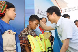 Phó Thủ tướng Chính phủ Vũ Đức Đam tặng áo phao cho các em nhỏ tại buổi lễ. (Ảnh: Thanh Tùng/TTXVN)
