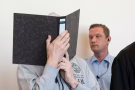 Nghi phạm (che mặt) bị cáo buộc 298 tội danh xâm hại trẻ em. (Nguồn: AFP)