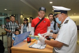 Khách đến từ những nước có dịch MERS-CoV được kiểm tra khu kiểm dịch sân bay Tân Sơn Nhất. (Ảnh: Phương Vy/TTXVN)