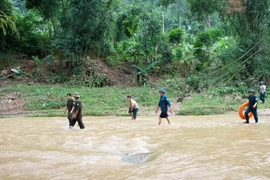 Lực lượng cứu hộ tìm kiếm người mất tích do nước lũ cuốn. (Ảnh: Thu Hằng/TTXVN)