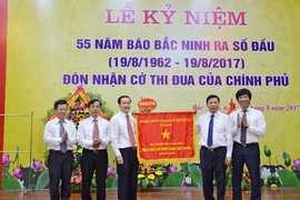 Thừa ủy quyền của Thủ tướng Chính phủ, ông Nguyễn Nhân Chiến - Bí thư tỉnh ủy Bắc Ninh trao cờ của Chính phủ cho ban lãnh đạo Báo Bắc Ninh. (Ảnh: Thanh Thương/Vietnam+)