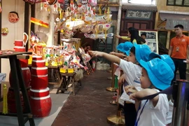 Các cháu thiếu nhi tham quan gian hàng đồ chơi trung thu truyền thống . (Ảnh: Đinh Thuận/TTXVN)