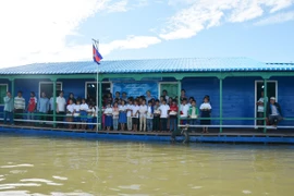 Các em học sinh kiều bào tại ngôi trường nổi tiễn chào đoàn công tác. (Nguyễn Lâm/Vietnam+)