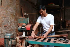 Anh Nguyễn Ngọc Du pha hàng gỗ tại xưởng sản xuất của gia đình. (Ảnh: Thanh Thương/TTXVN)