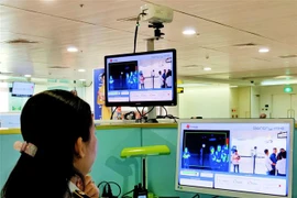 Nhân viên sân bay Tân Sơn Nhất kiểm tra màn hình hiển thị máy quét thân nhiệt đối với hành khách quốc tế đến Việt Nam. (Ảnh: Đinh Hằng/TTXVN)