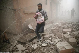 Người đàn ông bế một em bé sơ sinh chạy trên đường phố ở thị trấn Douma do phiến quân chiếm đóng, gần thủ đô Damascus. (Nguồn: Anadolu)