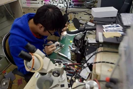 Một thợ sửa điện thoại tiến hành nâng cấp bộ nhớ trong iPhone. (Nguồn: CCTV)