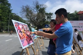 Khách tham quan khu trưng bày ảnh. (Ảnh: Đinh Thuận/TTXVN)