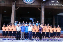 Đại sứ Nguyễn Bá Hùng (đeo kính) cùng các đại diện Cộng đồng người Việt tại Lào chụp ảnh lưu niệm với đội. (Ảnh: Phạm Kiên/Vietnam+)
