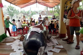 Người dân tiến hành nghi thức an táng cho cá voi. (Ảnh: Phước Ngọc/TTXVN)