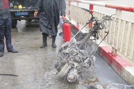 Chiếc xe máy cháy trụi khung trên cầu. (Ảnh: Sơn Bách/Vietnam+)