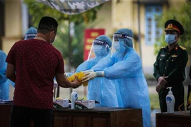 Các công dân nhận đồ dùng cá nhân cùng phương diện phòng chống dịch tại khu cách ly tập trung. (Ảnh: Trọng Đạt/TTXVN)