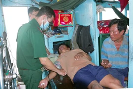 Quân y Bộ đội Biên phòng Sóc Trăng thăm khám sức khoẻ ban đầu cho 2 ngư dân gặp nạn. (Ảnh: Trung Hiếu/TTXVN)