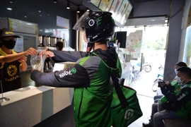 Tài xế Gojek nhận món ở nhà hàng để giao cho khách. (Ảnh: PV/Vietnam+)