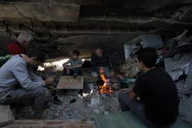 Người dân Palestine nhóm lửa sưởi ấm trong những căn nhà bị phá hủy bởi xung đột tại thành phố Khan Younis, Dải Gaza. (Ảnh: THX/TTXVN)