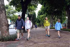 Các vị khách du lịch nước ngoài cũng chuẩn bị cho mình áo khoác mỏng để đón gió lạnh tại bờ hồ Hoàn Kiếm, Hà Nội. (Ảnh: Danh Lam/TTXVN)