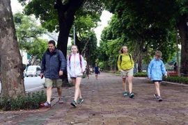 Các vị khách du lịch nước ngoài cũng chuẩn bị cho mình áo khoác mỏng để đón gió lạnh tại bờ hồ Hoàn Kiếm, Hà Nội. (Ảnh: Danh Lam/TTXVN)