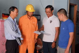 Cán bộ Điện lực hướng dẫn chủ nhà trọ giá bán điện theo quy định mới. (Ảnh: Phạm Cường/TTXVN)