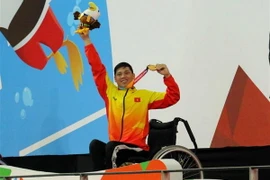 Vận động viên Võ Thanh Tùng tự hào giơ cao tấm Huy chương vàng thứ 3 tại Asian Para Games 2018. (Ảnh: Hải Ngọc/TTXVN)