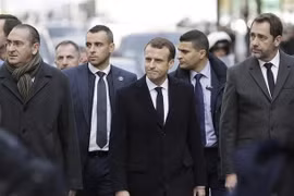 Tổng thống Pháp Emmanuel Macron (ở giữa) tới khu vực Khải Hoàn Môn ở thủ đô Paris để xem xét những thiệt hại do những đối tượng biểu tình quá khích gây ra. (Ảnh: AFP/TTXVN)