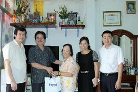 Ông Ngô Hà Thái, Phó Tổng Giám đốc Thông tấn xã Việt Nam, tặng quà cho bà Phương Bích Ngân là vợ Nhà báo liệt sỹ Thẩm Đức Hòa. (Ảnh: An Đăng/TTXVN)