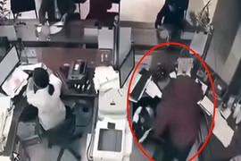 Tên cướp đang khống chế nhân viên ngân hàng. Ảnh cắt từ video. (Nguồn: Báo Đời sống và Pháp luật)
