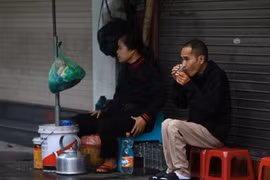 Thưởng thức cốc trà nóng trong mưa lạnh trên phố Trần Nhân Tông. (Ảnh: Hoàng Hiếu/TTXVN)