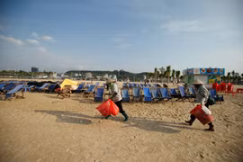 Dù mỗi ngày chịu tới 6 tấn rác thải nhưng chỉ sau một đêm, 4km bờ biển Bãi Cháy (Quảng Ninh) lại trở nên sạch đẹp, trắng tinh phơi mình đón nắng… Đó là nhờ công sức cần mẫn của đội nữ công nhân vệ sinh môi trường. (Ảnh: Vietnam+)