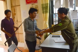 Người dân xã Cà Nàng huyện Quỳnh Nhai, tỉnh Sơn La đến trụ sở công an xã giao nộp súng. (Ảnh Công Luật/TTXVN) 