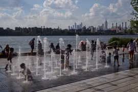 Trẻ em chơi đùa dưới vòi phun nước để tránh nóng tại New York, Mỹ, ngày 30/6/2021. (Ảnh: AFP/TTXVN)