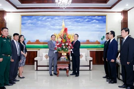 Đại sứ Việt Nam tại Lào Nguyễn Bá Hùng trao lẵnh hoa chúc mừng 66 năm Ngày thành lập Đảng NDCM Lào. (Ảnh: Phạm Kiên/TTXVN)