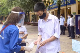 Thí sinh được sát khuẩn tay trước khi ra khỏi điểm thi. (Ảnh: Tuấn Đức/TTXVN)