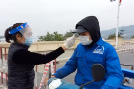Đo thân nhiệt người dân tại chốt kiểm soát dịch COVID-19. (Ảnh: Văn Đức/TTXVN)
