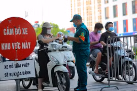 Các chốt kiểm soát của Ban chỉ đạo phòng chống dịch phường Vĩnh Tuy kiếm tra giấy tờ, thông tin của người ra, vào trên địa bàn. (Ảnh: Thanh Tùng/TTXVN)