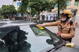 Cảnh sát giao thông dán phạt nguội đối với phương tiện dừng, đỗ trái phép trên phố Bà Triệu. (Ảnh: Doãn Tấn/TTXVN)