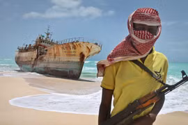 Cướp biển Somalia đứng cạnh một con tàu bị bắt. (Nguồn: AP)
