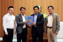 Tổng Giám đốc TTXVN Nguyễn Đức Lợi trao quà hỗ trợ đồng bào bị thiệt hại do mưa bão cho Phó Bí thư Thường trực Tỉnh ủy Quảng Nam Lê Văn Dũng. (Ảnh: Trịnh Bang Nhiệm/TTXVN)