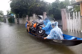 Mưa to gây ngập úng khiến người dân phải dùng thuyền để di chuyển tài sản đến nơi an toàn. (Ảnh: Trịnh Bang Nhiệm/TTXVN)