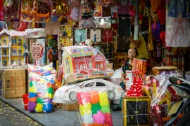 Tuy nhiên năm nay do ảnh hưởng của dịch COVID-19 nên lượng người mua bán đã giảm đi đáng kể, suốt dọc phố, cửa hàng bán vàng mã chỉ đếm trên đầu ngón tay. (Ảnh: Minh Hiếu/Vietnam+)