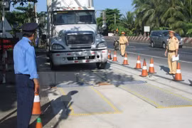 Lực lượng chức năng tiến hành kiểm soát tải trọng xe. (Ảnh: TTXVN)