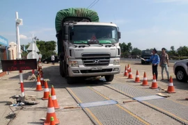 Lực lượng chức năng tiến hành kiểm tra tải trọng xe. (Ảnh: Thế Lập/TTXVN)