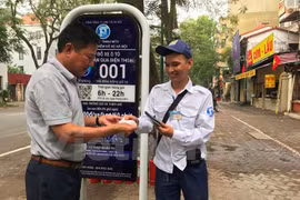 Khách hàng nhận hóa đơn từ nhân viên trông giữ phương tiện tại điểm đỗ sử dụng công nghệ iParking trên phố Lý Thường Kiệt. (Ảnh: Việt Hùng/Vietnam+)