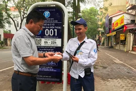 Khách hàng nhận hóa đơn từ nhân viên trông giữ phương tiện tại điểm đỗ sử dụng công nghệ iParking trên phố Lý Thường Kiệt. (Ảnh: Việt Hùng/Vietnam+)